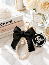 Load image into Gallery viewer, Black bow and pearl wristlet keychain with gold-tone hardware